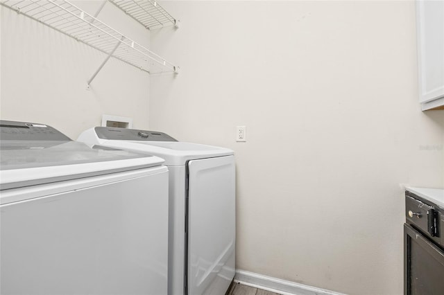 clothes washing area featuring cabinets and washing machine and dryer