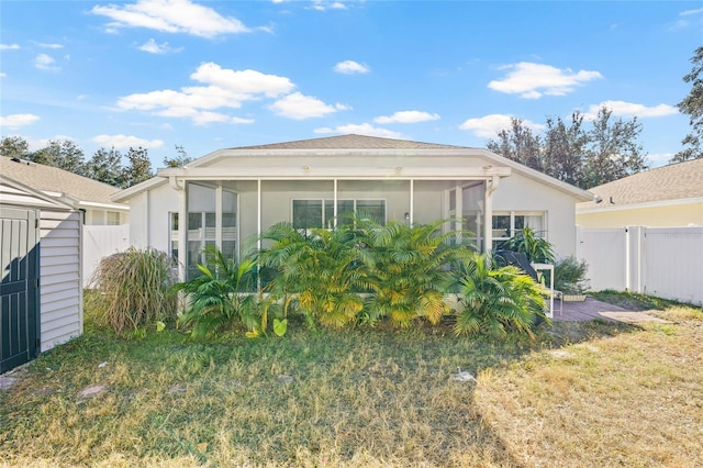 rear view of house with a lawn and a sunroom