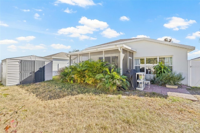 back of property featuring a yard, a shed, and a sunroom