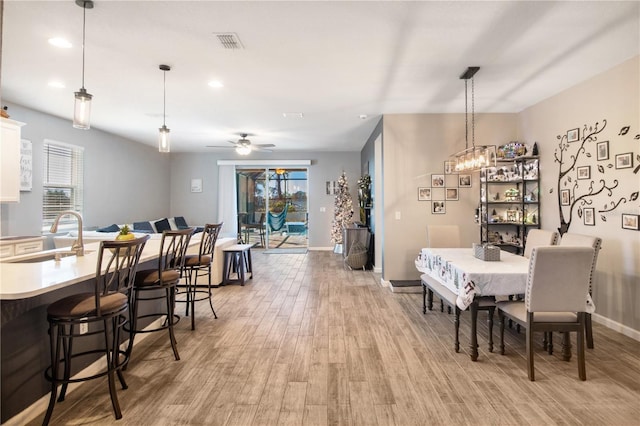 dining area with ceiling fan, light hardwood / wood-style floors, and sink