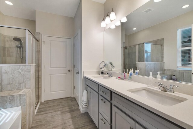 bathroom with hardwood / wood-style flooring, vanity, and a shower with door