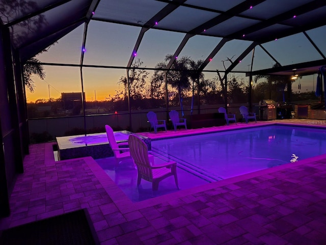 pool at dusk with a lanai and a patio