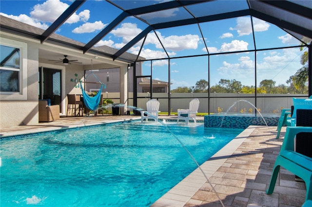 view of pool with glass enclosure, pool water feature, ceiling fan, and a patio