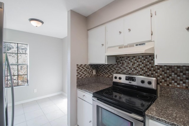 kitchen with tasteful backsplash, light tile patterned flooring, stainless steel range with electric cooktop, dark stone counters, and white cabinets