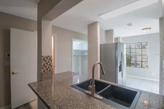 kitchen with kitchen peninsula, light tile patterned floors, sink, and stainless steel refrigerator with ice dispenser