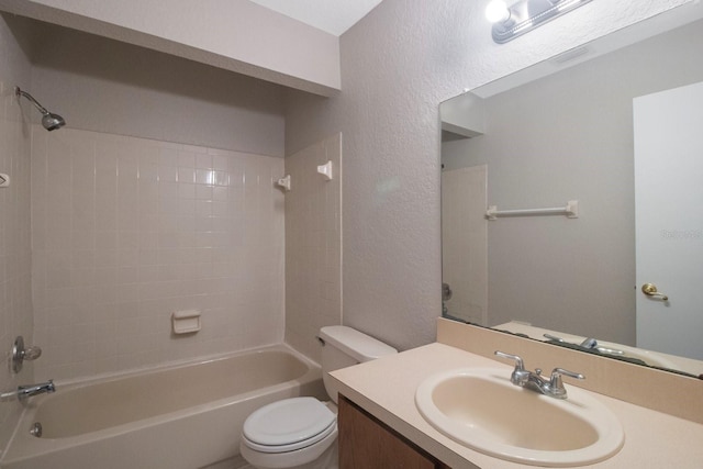 full bathroom featuring vanity, tiled shower / bath, and toilet