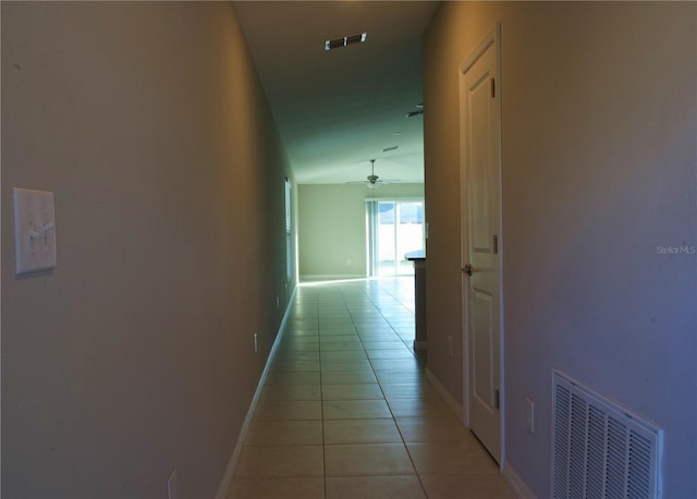 hallway with light tile patterned floors and lofted ceiling