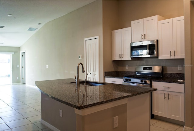 kitchen featuring a kitchen island with sink, sink, vaulted ceiling, white cabinetry, and stainless steel appliances