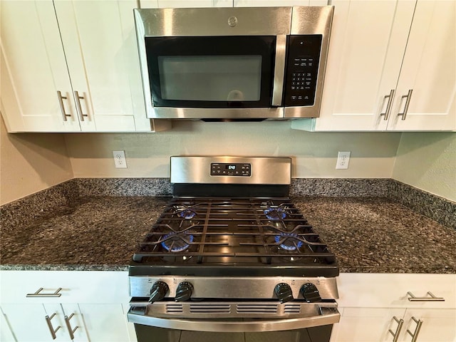 kitchen featuring white cabinets, appliances with stainless steel finishes, and dark stone countertops