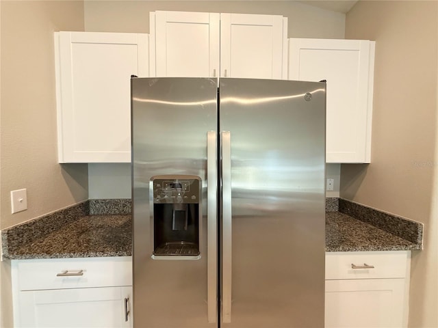 kitchen featuring white cabinets, stainless steel fridge with ice dispenser, and dark stone countertops