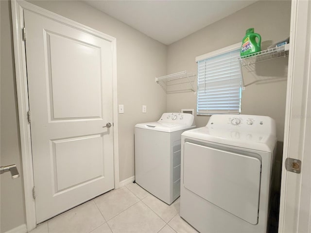 clothes washing area featuring light tile patterned floors and washer and dryer