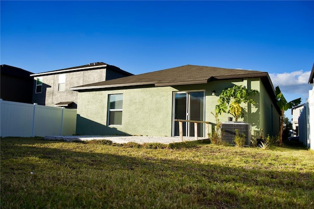 rear view of house with central AC and a lawn