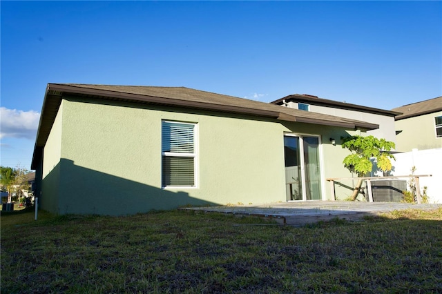 rear view of house featuring central AC unit and a lawn