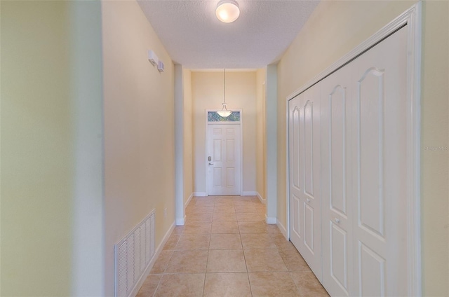 hall featuring light tile patterned floors and a textured ceiling