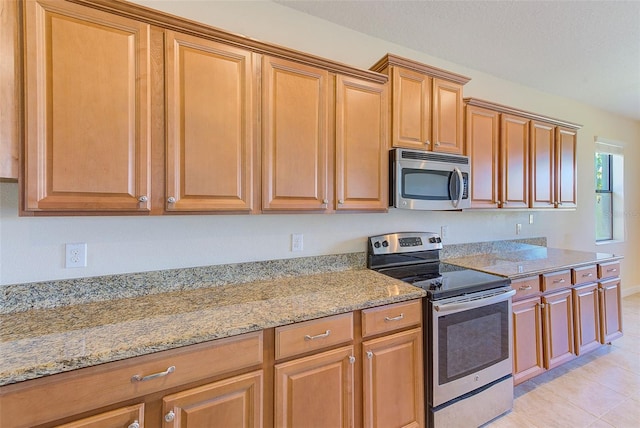 kitchen featuring light stone counters, light tile patterned flooring, and appliances with stainless steel finishes