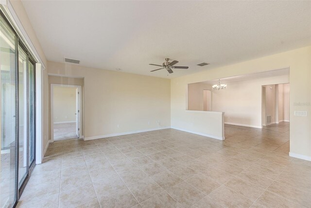 tiled spare room with ceiling fan with notable chandelier