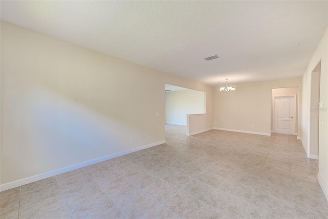 tiled empty room featuring a chandelier