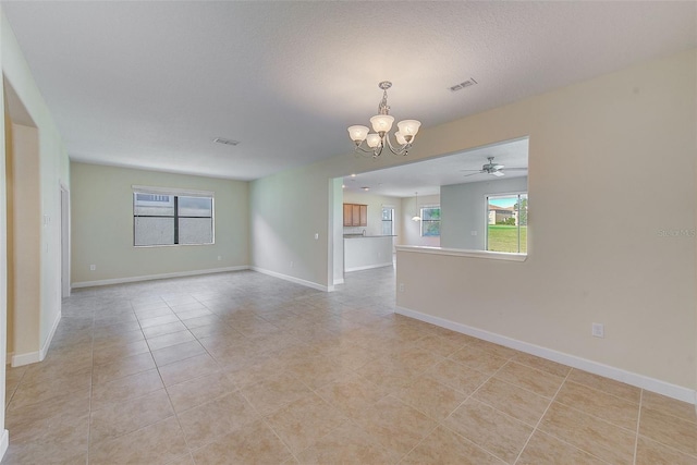 empty room featuring ceiling fan with notable chandelier, light tile patterned floors, and a textured ceiling