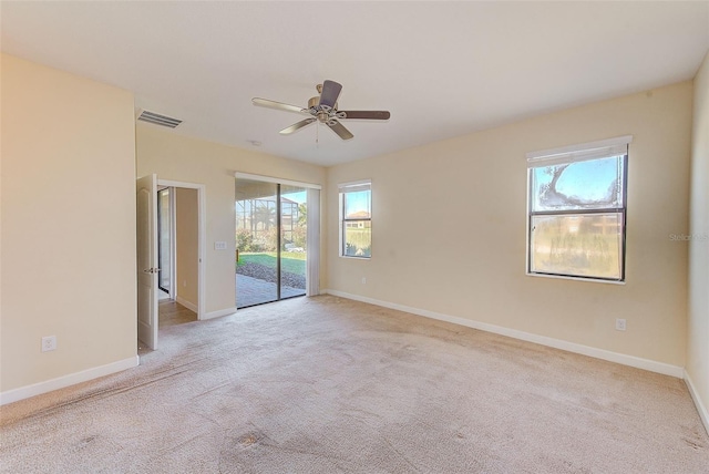 spare room featuring a wealth of natural light, ceiling fan, and light carpet