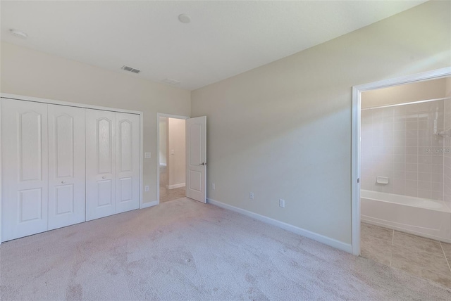 unfurnished bedroom with light colored carpet and a closet