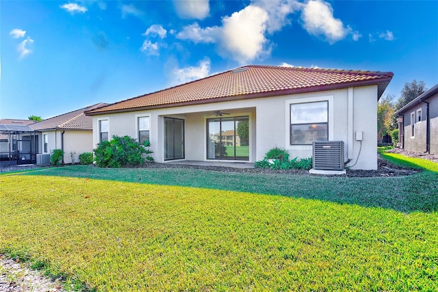 rear view of property featuring ceiling fan, central AC unit, and a lawn