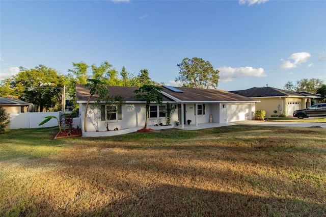 ranch-style home with a front yard, solar panels, and a garage