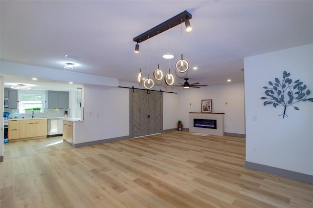 unfurnished living room featuring a barn door, light hardwood / wood-style floors, and ceiling fan