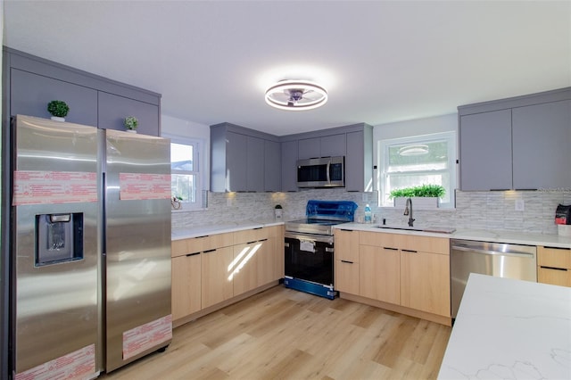 kitchen with stainless steel appliances, light hardwood / wood-style floors, gray cabinetry, and sink