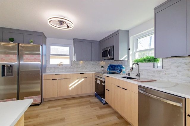 kitchen featuring gray cabinetry, a healthy amount of sunlight, stainless steel appliances, and light wood-type flooring