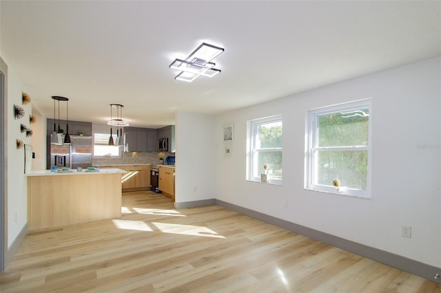 kitchen with kitchen peninsula, light wood-type flooring, electric range oven, backsplash, and light brown cabinets