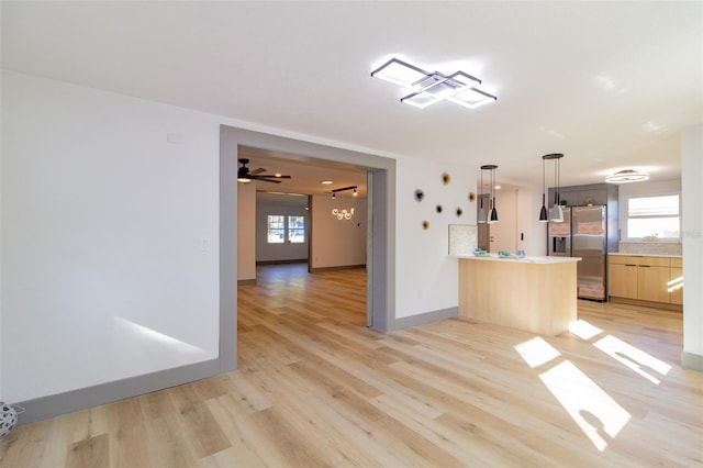 kitchen with kitchen peninsula, a healthy amount of sunlight, stainless steel refrigerator with ice dispenser, and light hardwood / wood-style floors