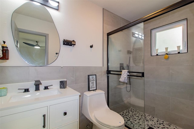 bathroom featuring vanity, toilet, a shower with shower door, and tile walls