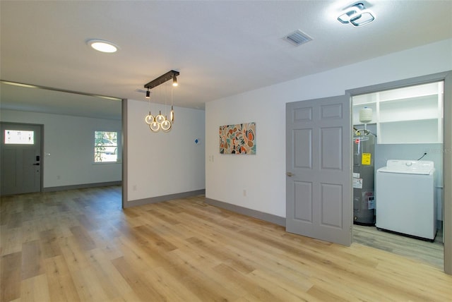 spare room featuring light wood-type flooring, washer / clothes dryer, and water heater