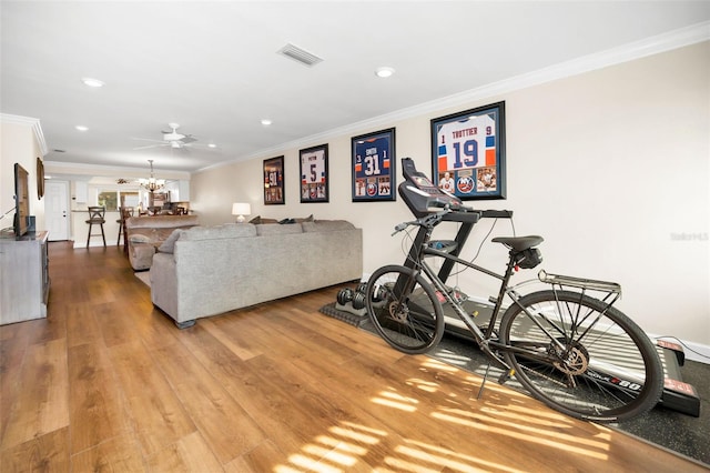 exercise room featuring hardwood / wood-style flooring, ornamental molding, and a notable chandelier