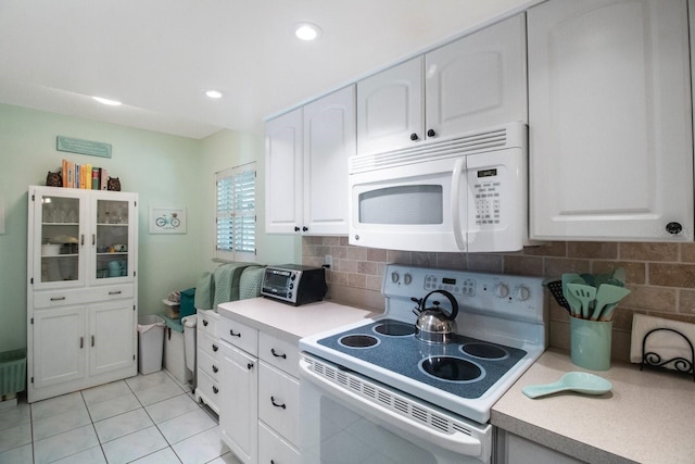 kitchen featuring light tile patterned floors, white appliances, white cabinetry, and backsplash