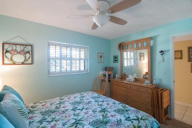 bedroom featuring ceiling fan, a textured ceiling, and multiple windows