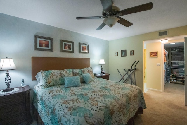 bedroom featuring light carpet, a closet, a spacious closet, and ceiling fan