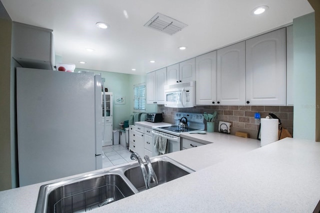 kitchen with white cabinetry, sink, backsplash, kitchen peninsula, and white appliances