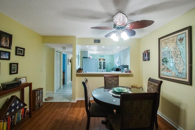 dining space featuring hardwood / wood-style flooring, a textured ceiling, and ceiling fan