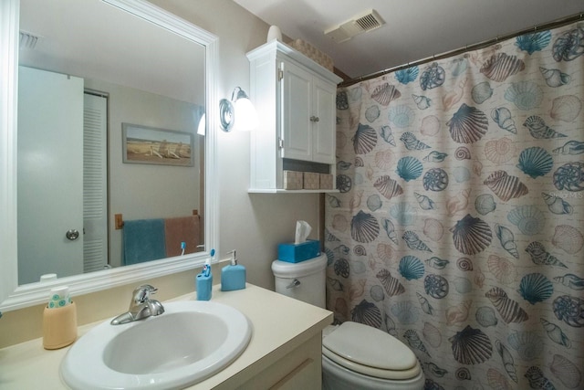 bathroom featuring vanity, walk in shower, and toilet