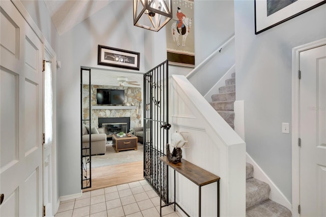 stairs with hardwood / wood-style floors, a stone fireplace, ceiling fan, and lofted ceiling