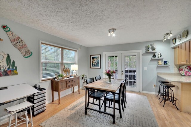 dining space featuring french doors, light hardwood / wood-style floors, and a healthy amount of sunlight