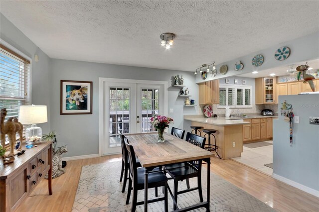 dining room with french doors, a textured ceiling, light hardwood / wood-style floors, and sink