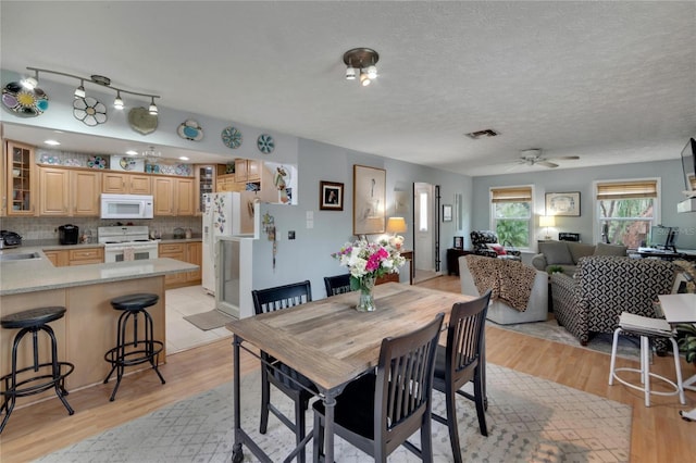 dining space with a textured ceiling, light hardwood / wood-style flooring, ceiling fan, and sink