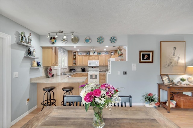 kitchen with white appliances, sink, light hardwood / wood-style flooring, light brown cabinetry, and kitchen peninsula