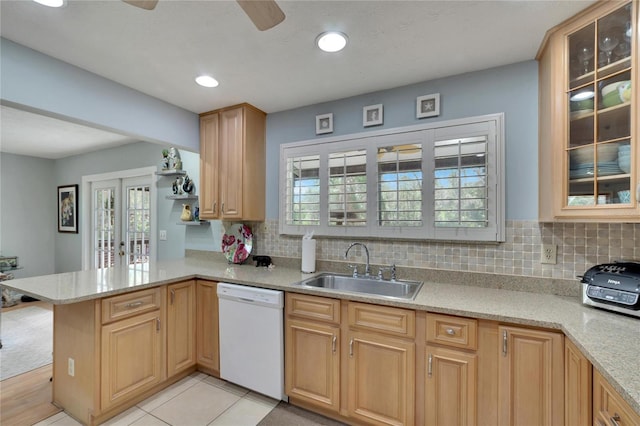 kitchen featuring white dishwasher, backsplash, kitchen peninsula, and sink