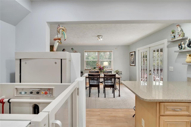 kitchen with light brown cabinetry, light wood-type flooring, a textured ceiling, and french doors