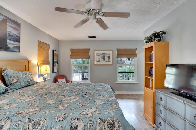 bedroom with multiple windows, ceiling fan, and a textured ceiling