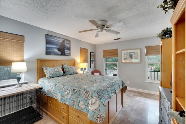 bedroom featuring multiple windows, ceiling fan, and a textured ceiling