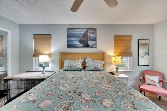 bedroom with ceiling fan, hardwood / wood-style floors, and a textured ceiling